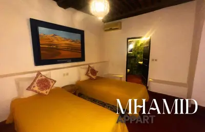 a room with two beds and a tv on the wall at mhamid hotel in Kasr Bounou