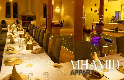 a dining room with tables and chairs with lights at mhamid hotel in Kasr Bounou