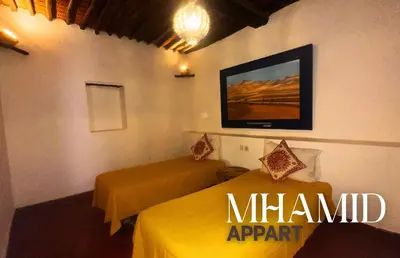 a room with two beds and a tv on the wall at mhamid hotel in Kasr Bounou