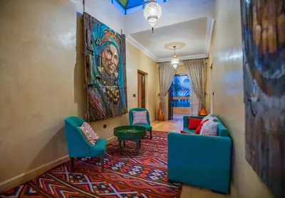 a living room with chairs and a painting on the wall at Domaine avec gouvernante 5 chambres, piscine, hamam et ferme pédagogique sur un hectare in Had Abdallah Rhiat