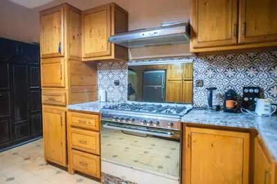 a kitchen with wooden cabinets and a stove top oven at Domaine avec gouvernante 5 chambres, piscine, hamam et ferme pédagogique sur un hectare in Had Abdallah Rhiat