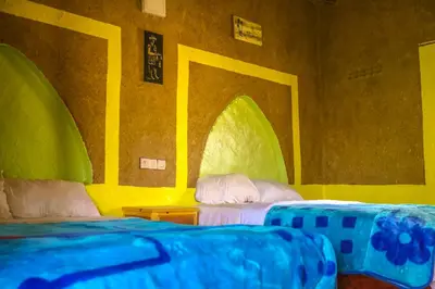 two beds in a room with yellow and green at Auberge Palacio Sidi Hamza in Tazrouft