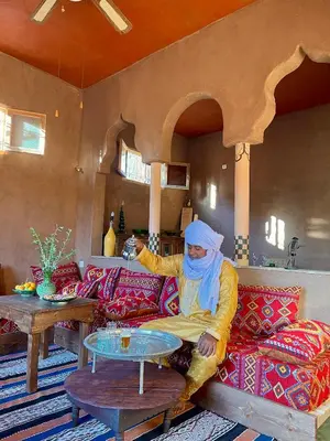 a woman sitting on a couch in a living room at Dar Zitoune - Authentic Stay in Tagounite in Tagounite