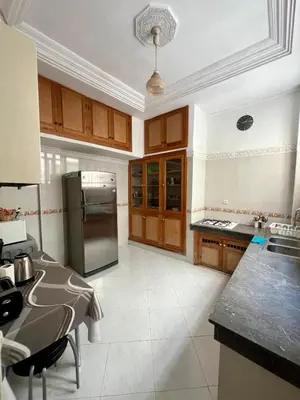 a kitchen with wooden cabinets and a stainless steel refrigerator at Large 3 Bedrooms Medina center Parking Secure in Fès