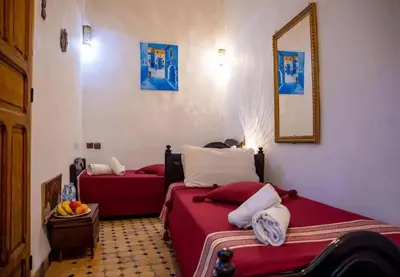 a room with two beds and a mirror on the wall at Riad misk lile fez in Fès