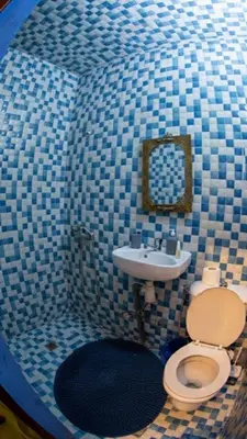 a blue tiled bathroom with a toilet and a sink at Riad misk lile fez in Fès