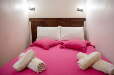 a pink bed with two pillows and towels on it at Riad misk lile fez in Fès