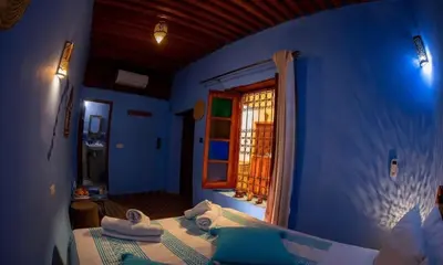 a blue room with a bed with a window at Riad misk lile fez in Fès