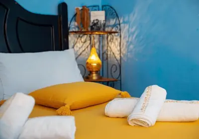 a bed with two towels and a yellow pillow at Riad misk lile fez in Fès