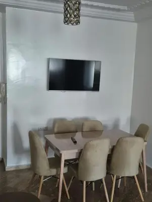 a dining room table with chairs and a television on a wall at Luxury Apartment in Fes City Centre for Families in Fès
