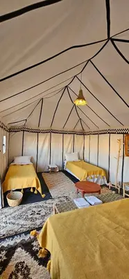 a tent with two beds and a table in it at Sunlight Desert Camp in Mhamid