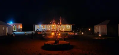 a building with a tree in front of it at night at Sunlight Desert Camp in Mhamid