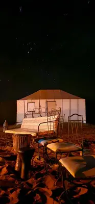 a bed and chairs in a room with a tent at Sunlight Desert Camp in Mhamid