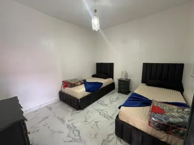 a bedroom with two beds and a marble floor at A unique and cute apartment in a prime location in Er Rachidia