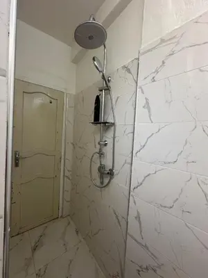 a bathroom with a shower with a white marble wall at A unique and cute apartment in a prime location in Er Rachidia