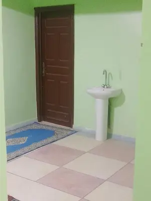 a bathroom with a brown door and a sink at Maison La Baraka Merzouga in Merzouga