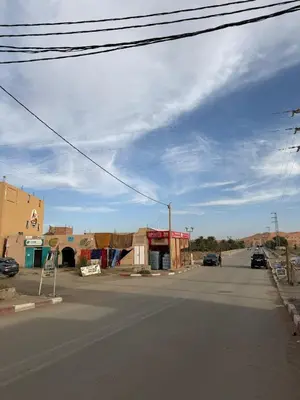 an empty street in a desert with a blue sky at Maison La Baraka Merzouga in Merzouga