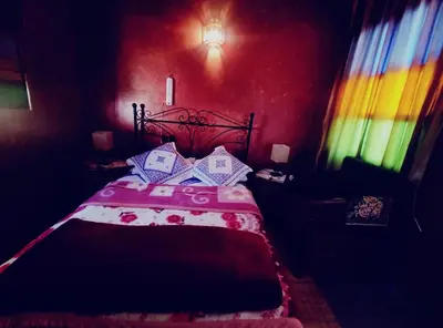 a bedroom with a bed with a red wall at Kasabah Senhaji in Moulay Idriss Zerhoun