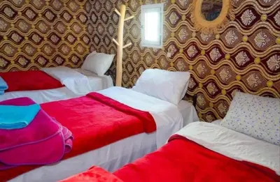 a room with three beds with red and white at Merzouga Camping Sahara in Hassilabied