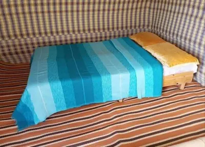 a small bed with a blue comforter on a couch at Merzouga Camping Sahara in Hassilabied
