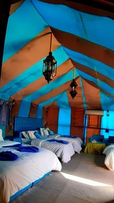 a bedroom with three beds in a tent at Sahara Waves Luxury Camp in Merzouga