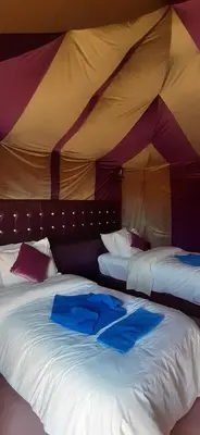 a bedroom with two beds in a tent at Sahara Waves Luxury Camp in Merzouga