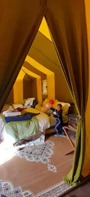 a room with two beds and two children in a tent at Sahara Waves Luxury Camp in Merzouga