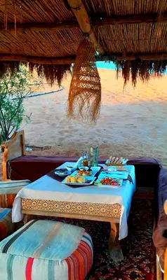 a table with a plate of food on the beach at Sahara Waves Luxury Camp in Merzouga