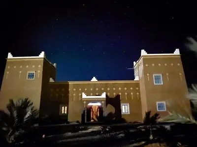 a building at night with a dress in the doorway at Guest house Kasbah Foum Tizza in Boikhlal