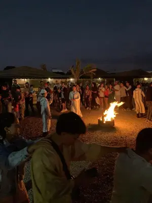 a group of people standing around a fire at Afraklie Camp in Merzouga