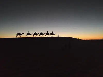 a group of people riding horses in the desert at Afraklie Camp in Merzouga