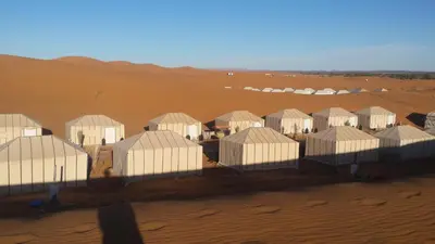a group of white buildings in a desert at Afraklie Camp in Merzouga