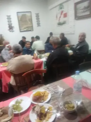 a group of people sitting at tables with plates of food at Hôtel monument historique situé au centre de la ville in Azrou