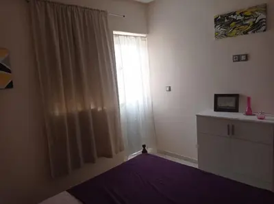 a bedroom with a bed and a window with a purple blanket at appartement neuf au premier etage in Fès