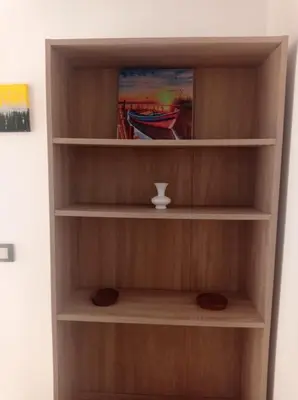 a book shelf with a cup and a painting at appartement neuf au premier etage in Fès