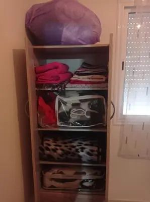 a closet filled with lots of clothes and a bed at appartement neuf au premier etage in Fès
