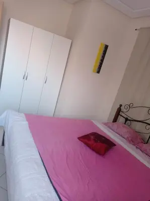 a bedroom with a large bed with a pink blanket at appartement neuf au premier etage in Fès