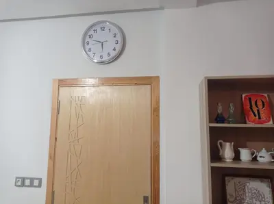 a clock on the wall above a wooden door at appartement neuf au premier etage in Fès