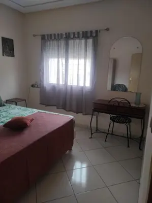 a bedroom with a bed and a desk and a mirror at rdc surélevé neuf a 10 min du centre ville in Fès