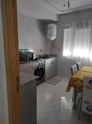 a kitchen with a washer and a table with a tableablish at rdc surélevé neuf a 10 min du centre ville in Fès