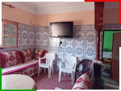 a living room with a couch and a tv on a wall at Spacious apartment for families near Ouzoud Falls in Azilal