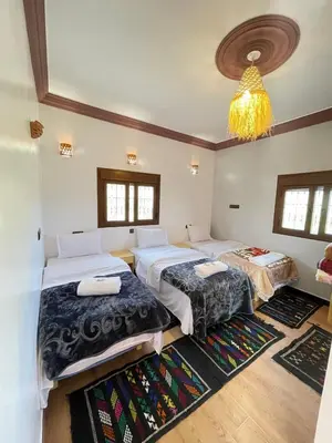 a bedroom with two beds and a chandelier at Auberge Restaurant Camping Taghzout in Agoudal