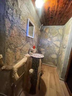 a bathroom with a sink in a stone wall at Auberge Restaurant Camping Taghzout in Agoudal
