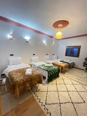a room with two beds and a chandelier at Auberge Restaurant Camping Taghzout in Agoudal