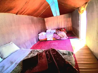 a small room with two beds in a tent at Tigmi Desert Camp in Merzouga
