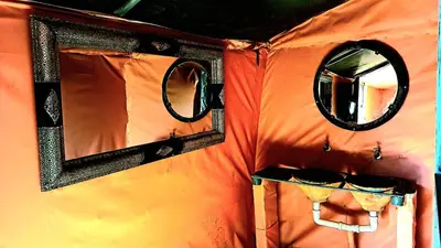an orange tent with two windows and a mirror at Tigmi Desert Camp in Merzouga