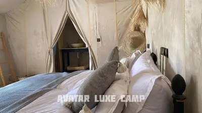 a person laying on a bed in a tent at Avatar Luxe Camp in Merzouga