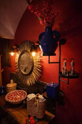 a room with a red wall with a mirror and a vase at dar d'art Marrakech in Sraïri