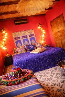 a bedroom with a bed with purple sheets and pillows at dar d'art Marrakech in Sraïri