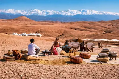 a group of people sitting on a blanket in the desert at dar d'art Marrakech in Sraïri
